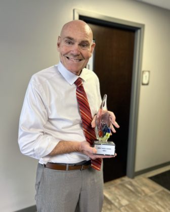 A photo of somene holding a award at a ceremony.
