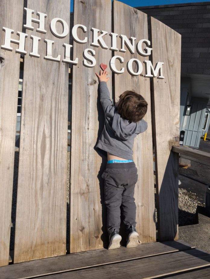 A child playing near a Hocking Hills sign.