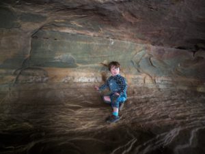 A child exploring the inside of a cave.