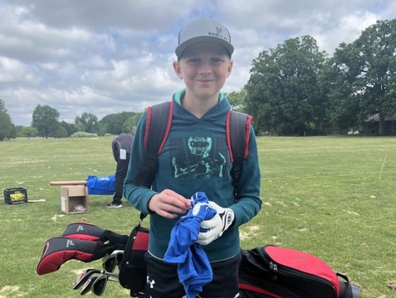 A kid standing by a dirt bike.