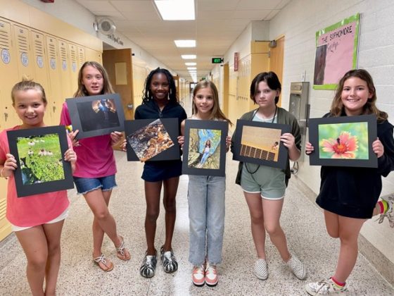 A group of kids holding up artwork.