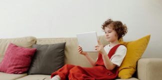 A child sitting on the couch on their device.