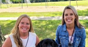A photo of two people next to a dog.