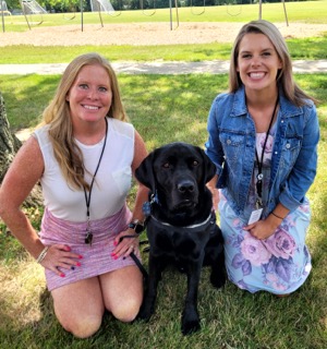 A photo of two people next to a dog.