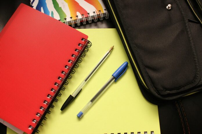 Notebooks and pens laying on a desk.