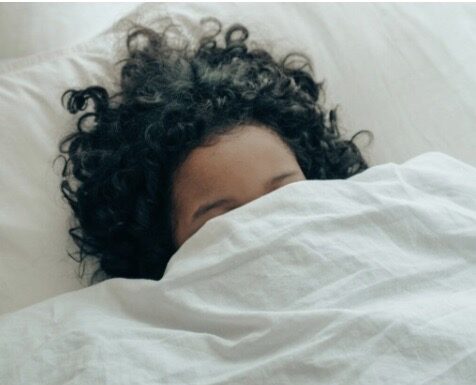 A person covering her face in a blanket.