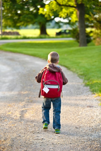 A child walking to school with a backpack on.