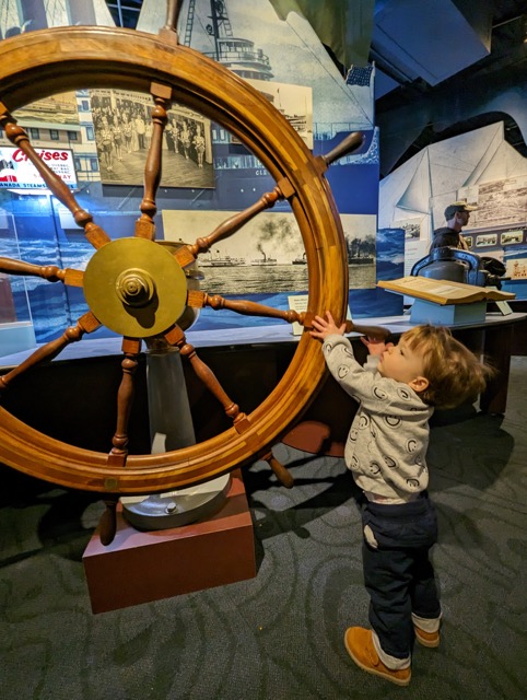 A photo of a child next to a large wheel.