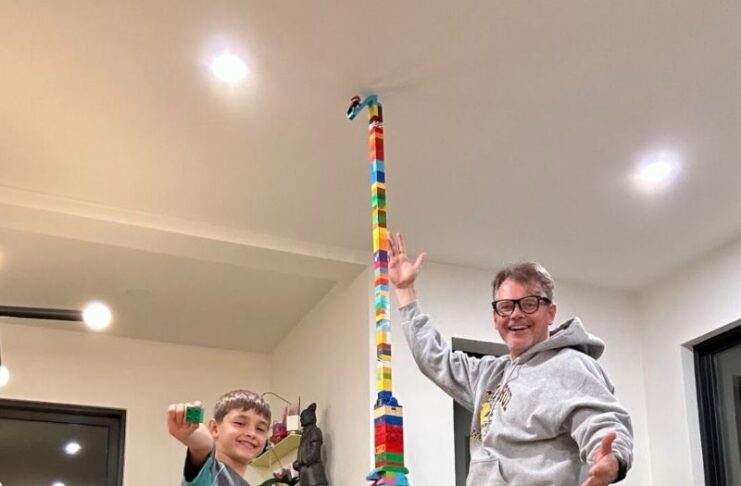 Father and sons displays their tall lego building