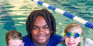 Instructor holding kids in water during swim lessons