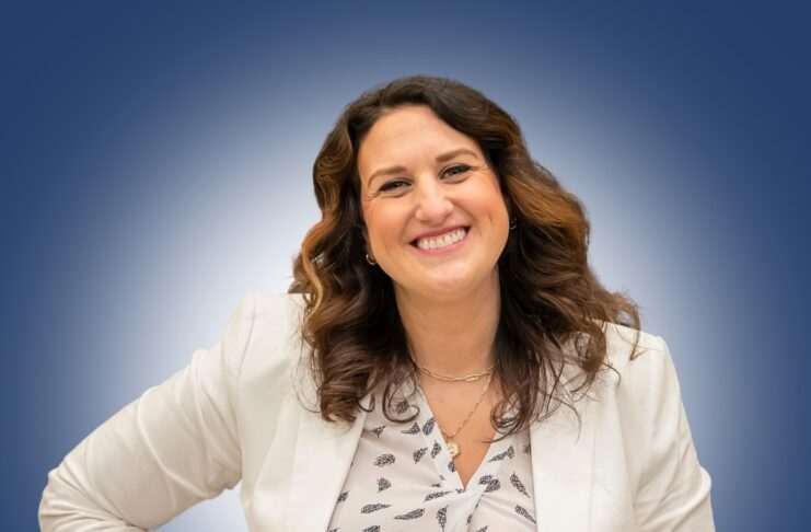 Woman standing in white jacket against blue background