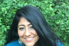 Women in blue shirt in front of greenery