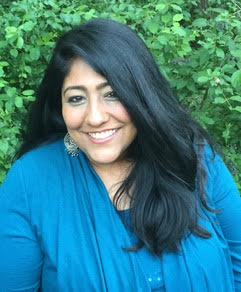 Women in blue shirt in front of greenery