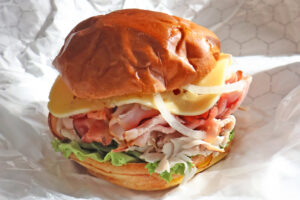 The Harvest club stack comes piled high with all-natural smoked turkey and fire-roasted ham, bacon slices, Swiss cheese, lettuce, tomato and onion on a brioche bun.