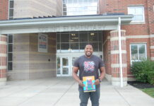 man holding book in front of school