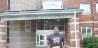 man holding book in front of school
