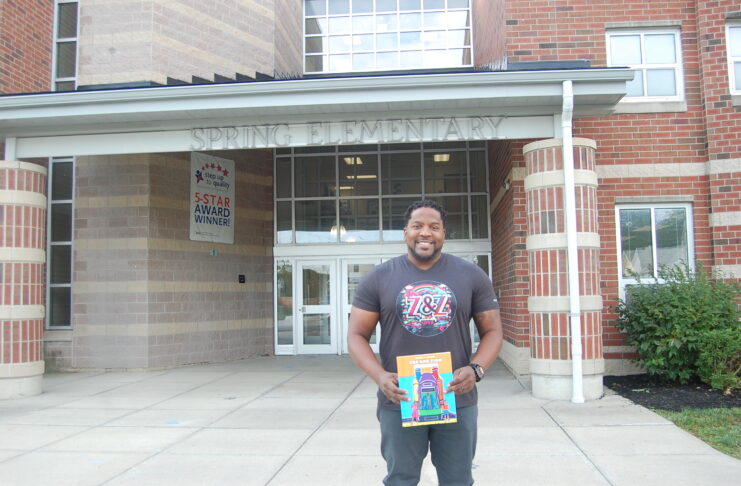 man holding book in front of school