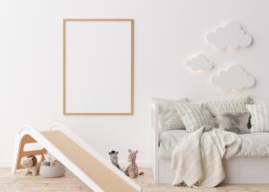 Empty vertical picture frame on white wall in modern child room.