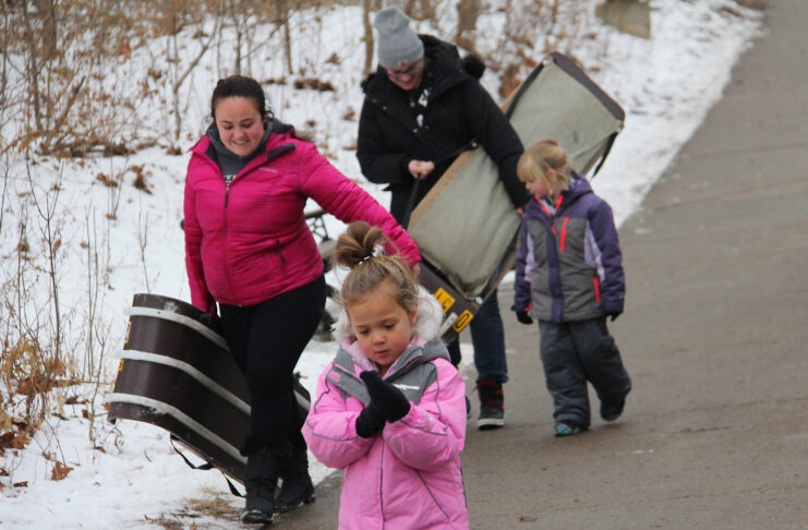 Family holding toboggan sleds