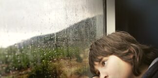Young boy looking out window and looking sad