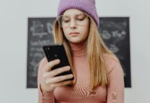 Teen girl in hat looking and smart phone