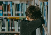 kid with head on bookshelf