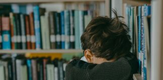 kid with head on bookshelf